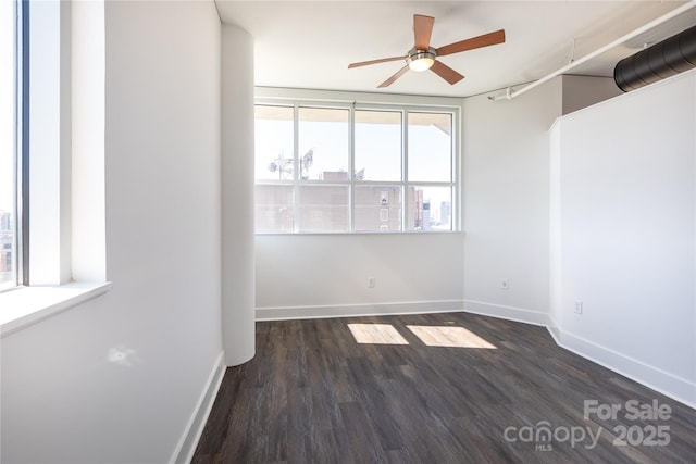 empty room with baseboards, dark wood-type flooring, and a ceiling fan