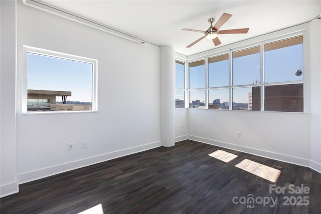 spare room featuring baseboards, ceiling fan, and dark wood-style flooring