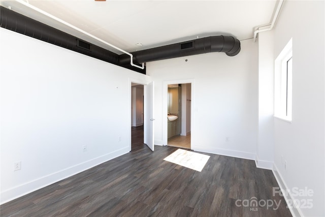 unfurnished room featuring visible vents, baseboards, and dark wood-style floors