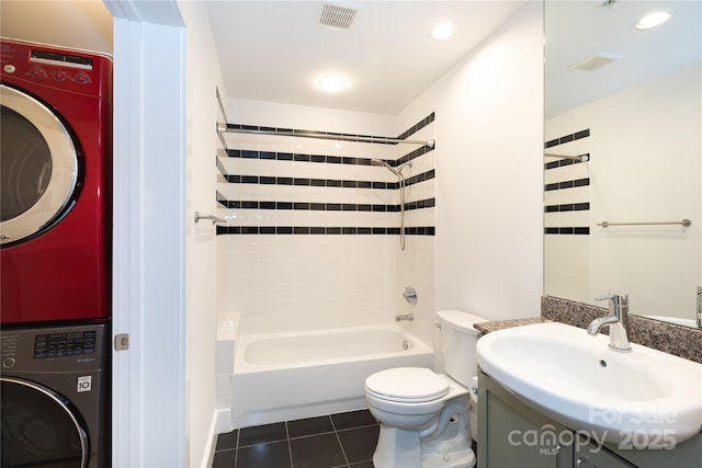 full bath with visible vents, tub / shower combination, tile patterned flooring, stacked washer / drying machine, and toilet