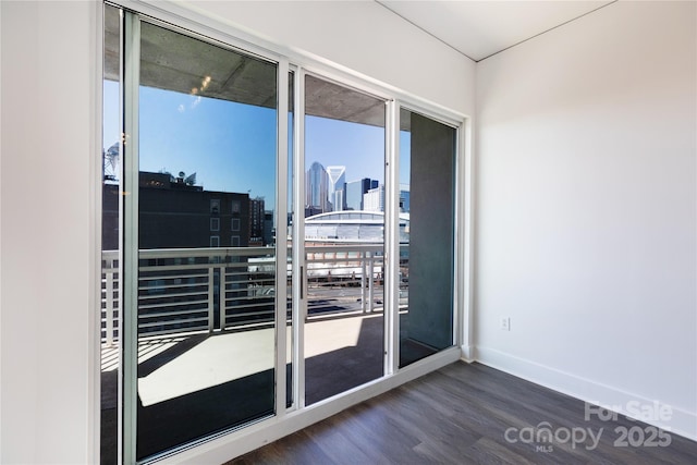 doorway with dark wood finished floors, a city view, and baseboards