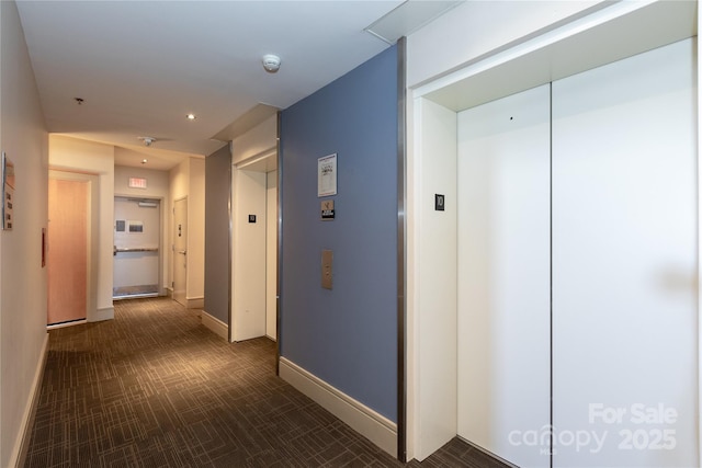 hallway with baseboards and elevator