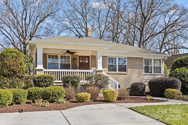 view of front of house featuring a shingled roof, a ceiling fan, a chimney, a porch, and brick siding