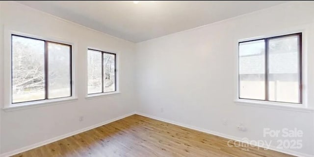 empty room with baseboards, a healthy amount of sunlight, and light wood-style floors