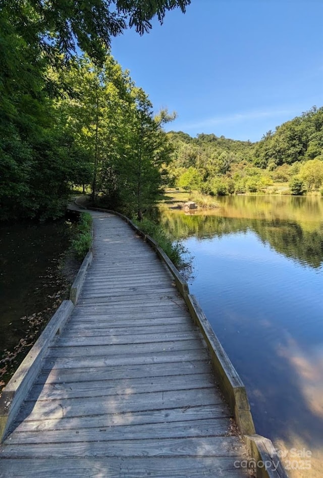 view of dock with a water view and a forest view