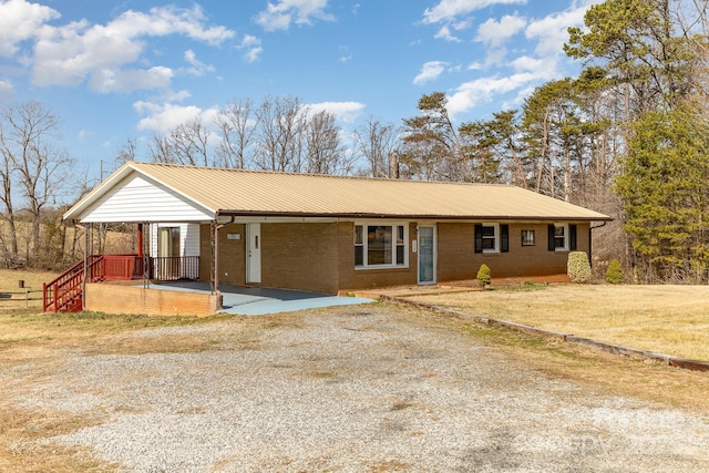 ranch-style house with driveway, brick siding, metal roof, a front yard, and a porch