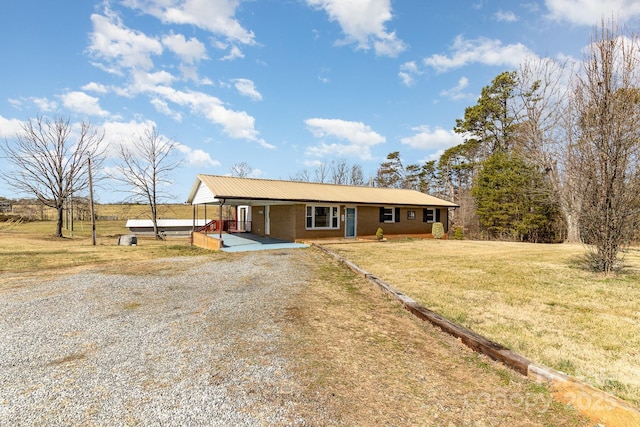 view of front of property with a front yard, a carport, and gravel driveway