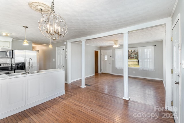 kitchen featuring appliances with stainless steel finishes, ornate columns, wood finished floors, and a sink