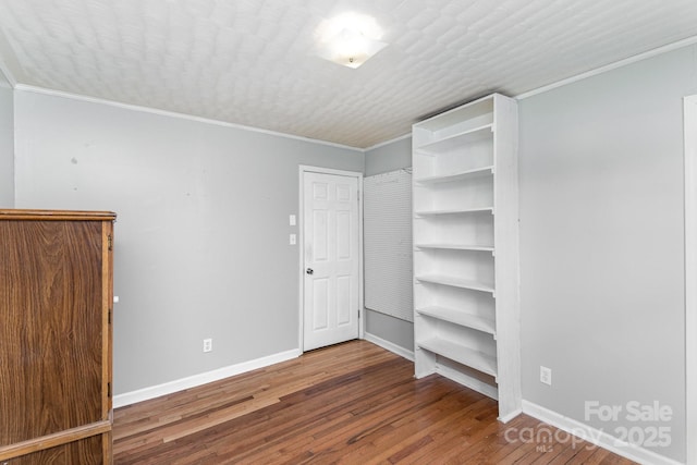 unfurnished bedroom featuring crown molding, baseboards, wood finished floors, and a textured ceiling