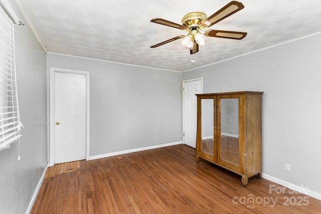 empty room with baseboards, a ceiling fan, wood finished floors, and ornamental molding