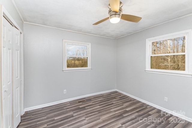 unfurnished bedroom with a closet, dark wood-type flooring, baseboards, and a ceiling fan