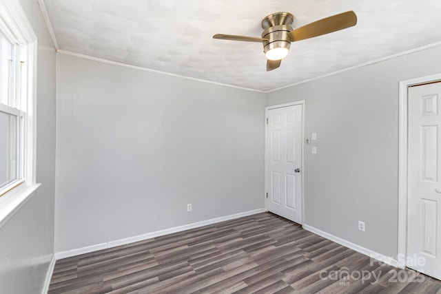 spare room with ornamental molding, dark wood finished floors, baseboards, and a ceiling fan