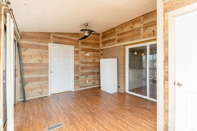 interior space with wood walls, lofted ceiling, wood finished floors, and visible vents