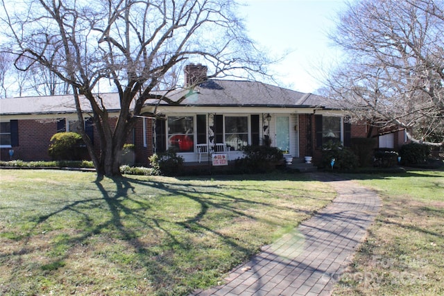 single story home with brick siding, a chimney, and a front yard