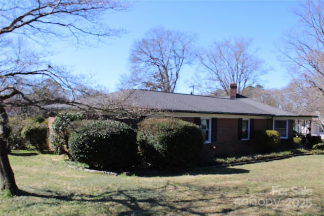 view of side of property with a lawn and a chimney