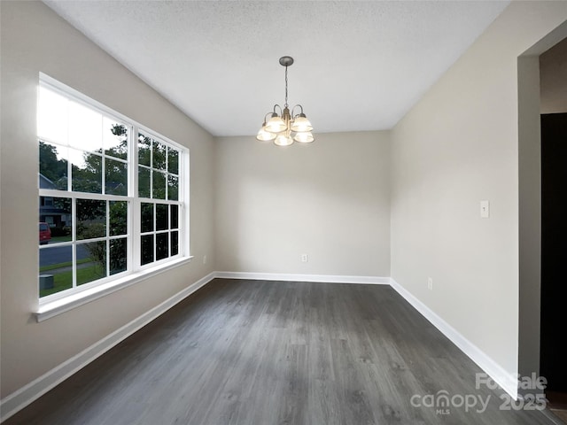 unfurnished dining area featuring a chandelier, a textured ceiling, and dark hardwood / wood-style flooring