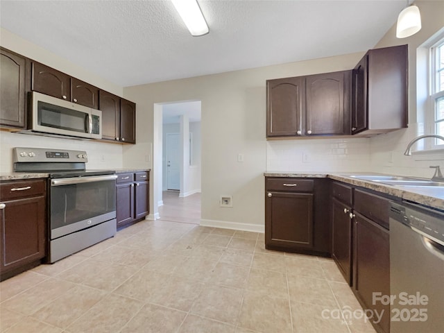 kitchen with sink, tasteful backsplash, hanging light fixtures, dark brown cabinets, and stainless steel appliances