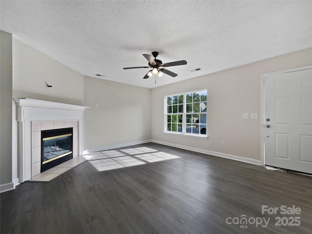 unfurnished living room featuring a tiled fireplace, hardwood / wood-style flooring, a textured ceiling, and ceiling fan