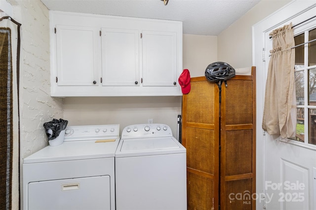 laundry area with cabinets, independent washer and dryer, and a textured ceiling