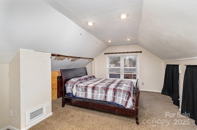 bedroom with light carpet, vaulted ceiling, and a textured ceiling