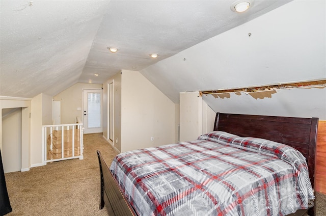 bedroom with vaulted ceiling, light carpet, and a textured ceiling