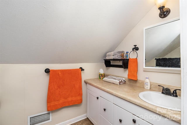 bathroom with vanity, vaulted ceiling, and a textured ceiling