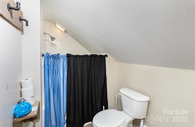 bathroom with lofted ceiling, curtained shower, a textured ceiling, and toilet