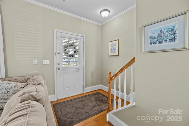 entrance foyer with ornamental molding, wood finished floors, and baseboards