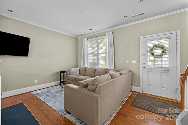 living area featuring ornamental molding, light wood finished floors, and visible vents