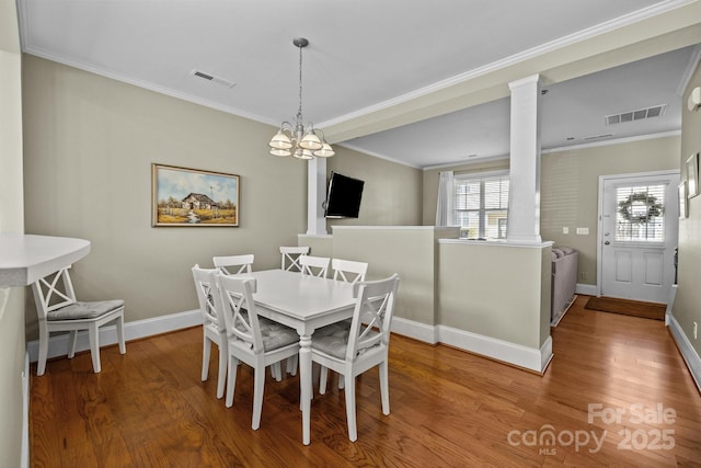 dining space with ornate columns, visible vents, and wood finished floors