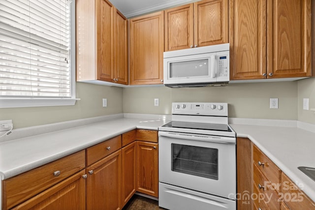 kitchen featuring brown cabinetry, white appliances, and light countertops