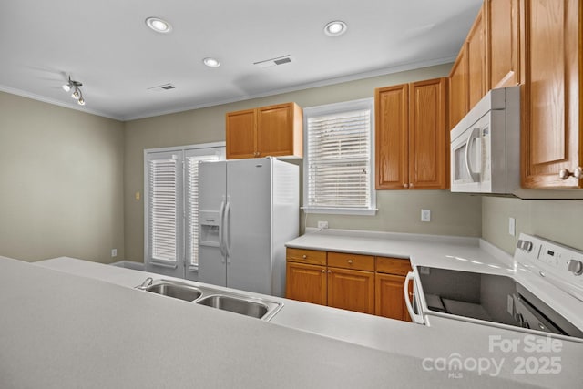 kitchen featuring white appliances, a sink, light countertops, built in desk, and recessed lighting