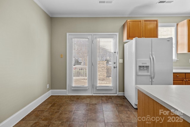 kitchen with white refrigerator with ice dispenser, baseboards, visible vents, light countertops, and dark tile patterned floors