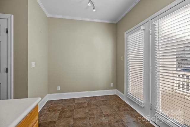 interior space featuring rail lighting, baseboards, and ornamental molding