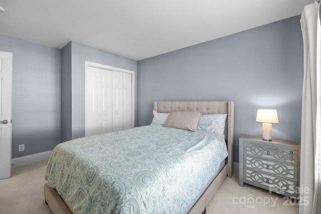 bedroom featuring baseboards, a closet, and light colored carpet