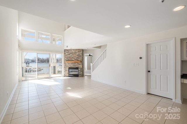 unfurnished living room with a fireplace, light tile patterned floors, recessed lighting, baseboards, and stairs