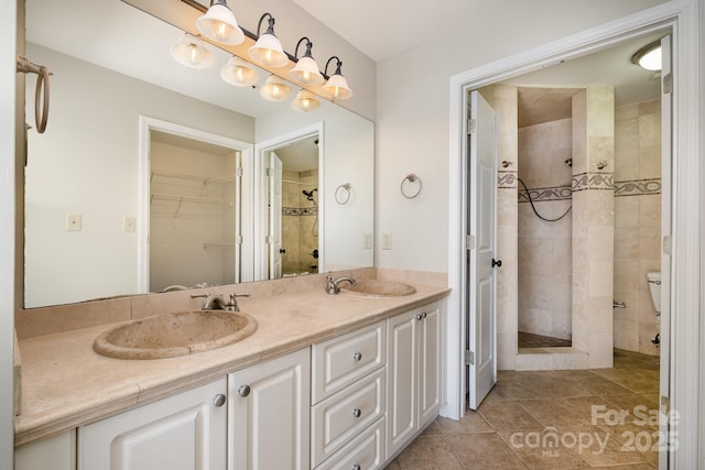 full bathroom featuring double vanity, a stall shower, tile patterned flooring, and a sink