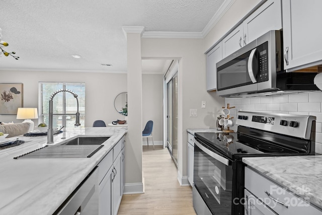 kitchen featuring backsplash, ornamental molding, sink, and appliances with stainless steel finishes