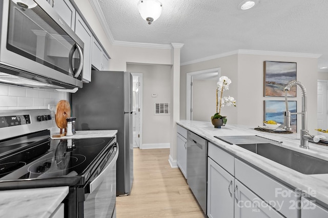 kitchen featuring ornamental molding, stainless steel appliances, sink, and gray cabinetry