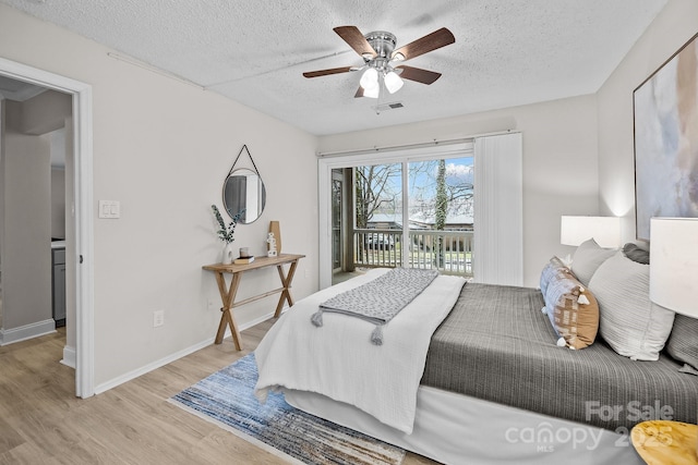 bedroom with ceiling fan, access to exterior, light hardwood / wood-style floors, and a textured ceiling