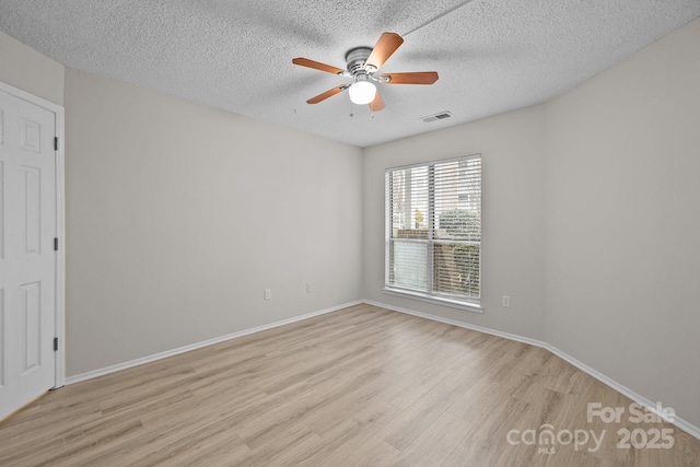 empty room with a textured ceiling, ceiling fan, and light hardwood / wood-style flooring