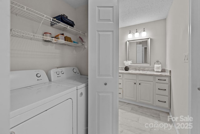 washroom featuring sink, washer and clothes dryer, and a textured ceiling