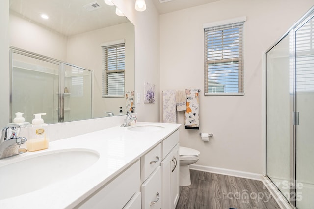 bathroom featuring a shower with door, wood-type flooring, vanity, and toilet