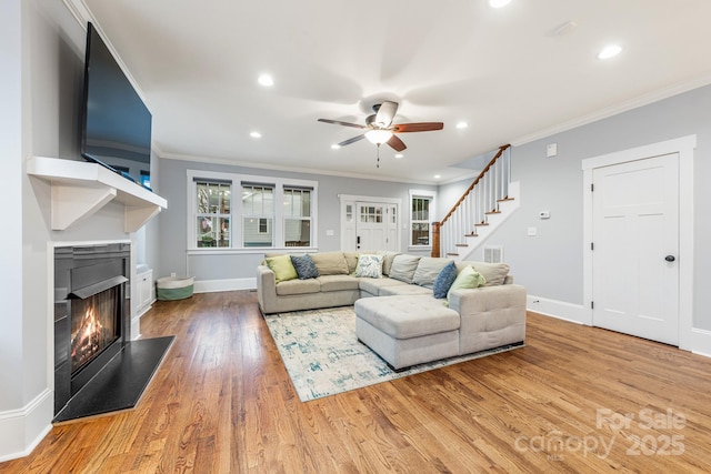 living room featuring wood-type flooring, ornamental molding, and ceiling fan