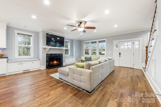 living room with ornamental molding, a healthy amount of sunlight, a fireplace, and light hardwood / wood-style floors