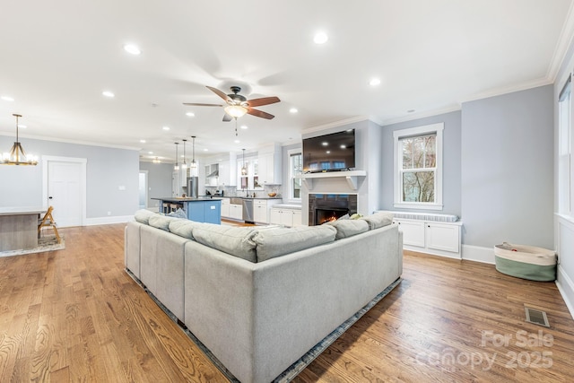 living room with ornamental molding, a fireplace, and light hardwood / wood-style flooring