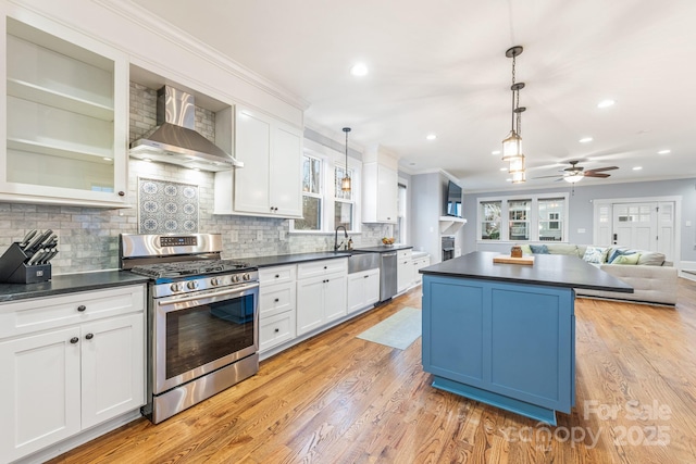 kitchen with stainless steel appliances, white cabinetry, and wall chimney range hood