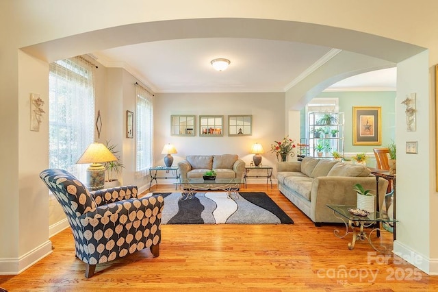 living area featuring arched walkways, ornamental molding, baseboards, and wood finished floors