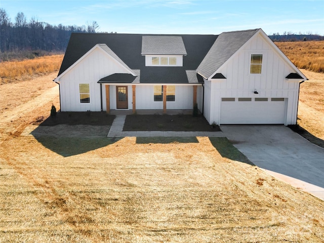 modern farmhouse style home with driveway, a garage, a shingled roof, board and batten siding, and a front yard