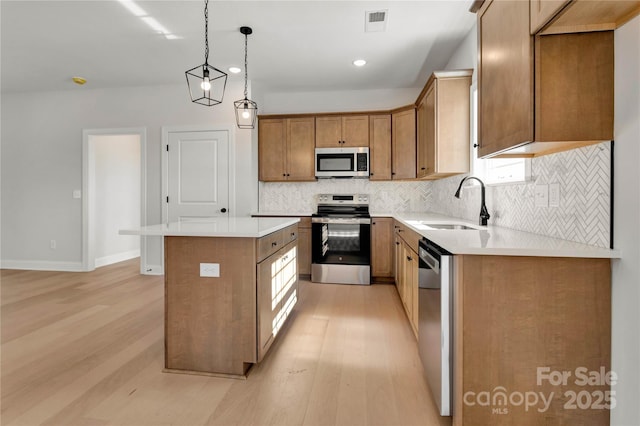 kitchen with a kitchen island, appliances with stainless steel finishes, light countertops, and a sink